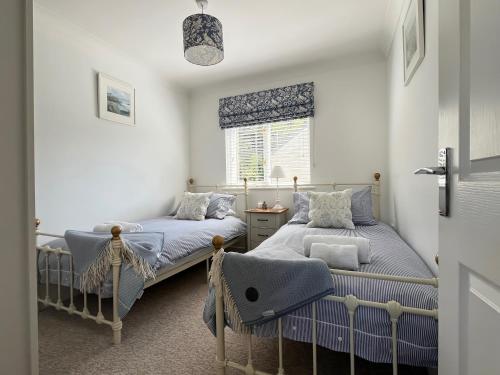 a bedroom with two beds and a window at Breeze Cottage in Falmouth