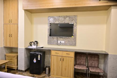 a kitchen with two chairs and a tv on the wall at Popli Paradise Resort in Jaipur