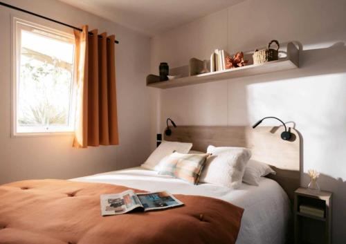 ein Schlafzimmer mit einem Bett, auf dem ein Buch liegt in der Unterkunft Camping 4 étoiles - Parc aquatique - ccadfdf in Saint-Jean-de-Monts