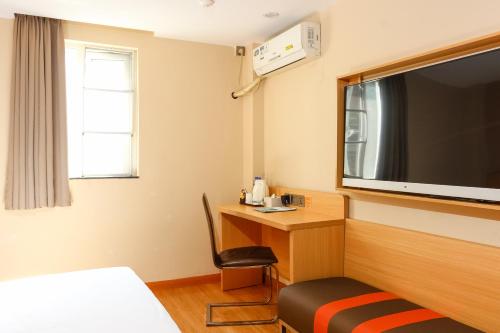 a hotel room with a desk and a tv on the wall at 7Days Premium Guangzhou Tianhe Shipaiqiao in Guangzhou
