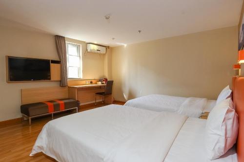 a hotel room with two beds and a television at 7Days Premium Guangzhou Tianhe Shipaiqiao in Guangzhou