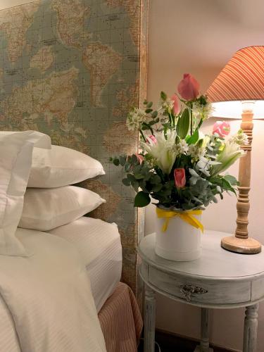a vase of flowers on a table next to a bed at Hotel MasClara in Villa de Leyva