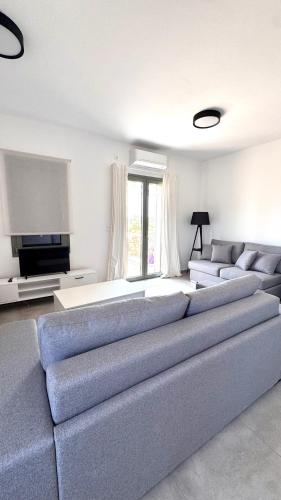 a living room with a large couch and a tv at Aroniadika rooms in Kýthira