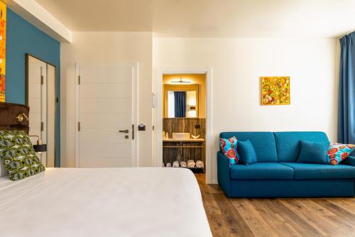 a bedroom with a bed and a blue couch at Hotel Rovereto in Rovereto