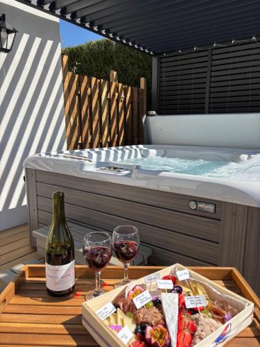 une table avec des verres à vin et un plateau de nourriture et un bain à remous dans l'établissement Spa privé & évasion polynésienne à 20 min de Fontainebleau - PrestigeLodges, à Pamfou