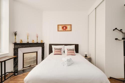 - une chambre avec un lit blanc et une cheminée dans l'établissement La Teranga de Kadi & Cathy, avec jardin privatif, à Nancy