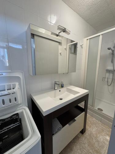 une salle de bain blanche avec un lavabo et une douche dans l'établissement Front de mer T2 balcon, jardin, garage, proche commerces, à Valras-Plage