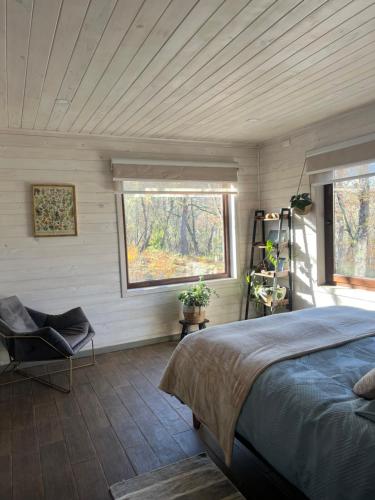 a bedroom with a bed and a window and a chair at Refugio Vista Sierra Nevada in Malalcahuello