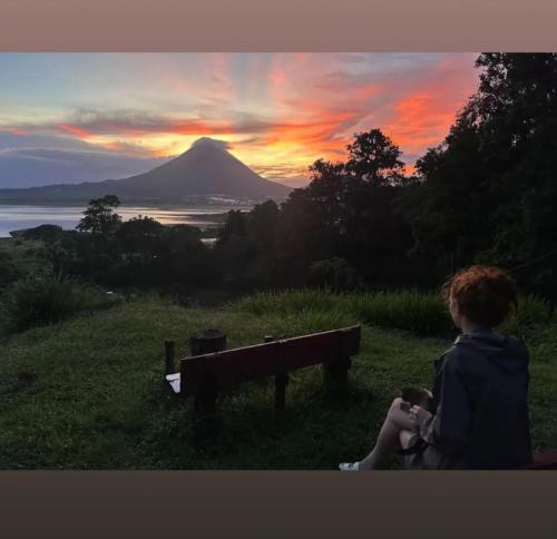 a person sitting on a bench looking at a mountain at Arenal Base Camp in El Castillo de La Fortuna