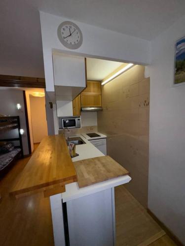 a kitchen with a counter and a clock on the wall at Canigou 45 by CONFORTSKY in Pas de la Casa