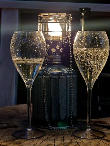 two wine glasses sitting on a table next to a bottle at Glamping Štôla Brezovy vanok in Vyšné Hágy