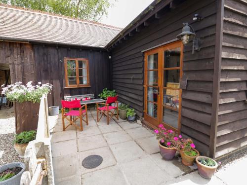 a patio with a table and chairs next to a house at Robbie's Barn in Halford