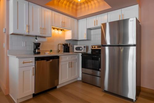 a kitchen with white cabinets and a stainless steel refrigerator at Monaco Vacation Rentals in Clearwater Beach