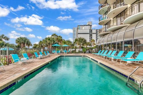 a swimming pool with lounge chairs and a building at Meridian Plaza 307! Third Floor Ocean Views! Sleeps 4! in Myrtle Beach