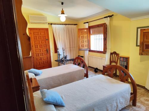 a bedroom with two beds and a table and chairs at Precioso chalet con gran algarrobo y piscina privada in La Jara