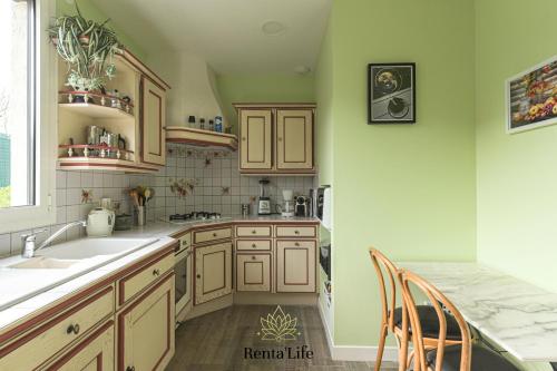 - une cuisine avec des murs verts et des placards en bois dans l'établissement Cassassiens Reneuves - Maison T4 - 7min DisneyLand, à Chessy