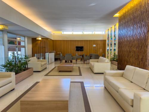 a lobby with white couches and a dining room at Arituba Park Hotel in Natal