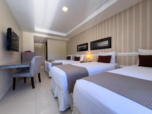 a hotel room with four beds and a television at Arituba Park Hotel in Natal