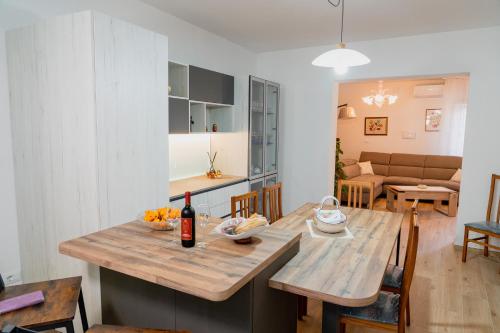 a kitchen and living room with a table with a bottle of wine at Casa di Samu in Bauladu