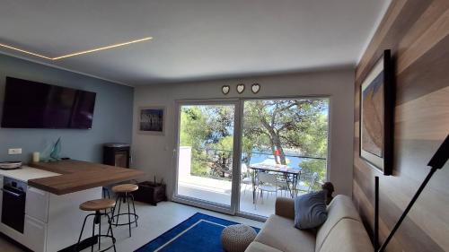 a living room with a couch and a kitchen with a sliding glass door at House Holiday Lodge in Žirje