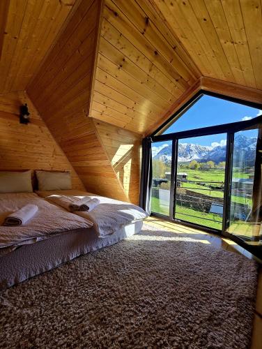 a bedroom with a bed and a large window at Grand Mountain Cottage in Kazbegi