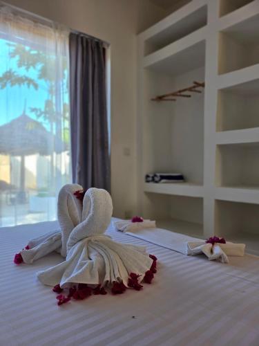 a bedroom with a bed with a towel angel on it at Mfumbwi Twins Apartments in Jambiani
