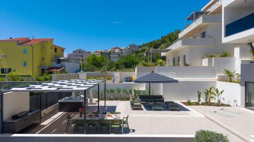 un patio con tavoli, sedie e ombrelloni di Villa Siete Luxury Living Just Steps from the Beach a Duće