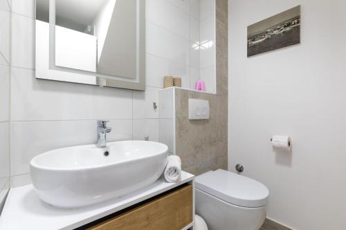 a white bathroom with a sink and a toilet at House Punat Residence in Punat