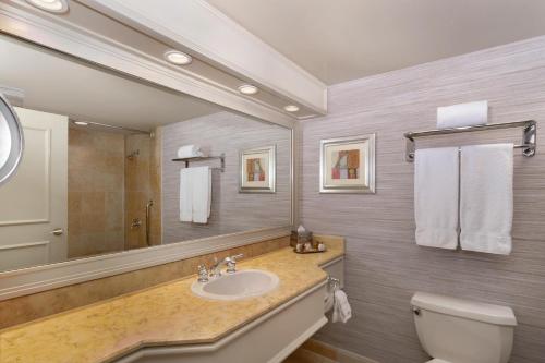 a bathroom with a sink and a toilet and a mirror at Treasure Island TI Las Vegas - Handwritten Collection in Las Vegas