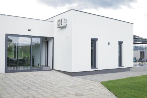 a white house with glass doors and a patio at Danka Pool House in Usije
