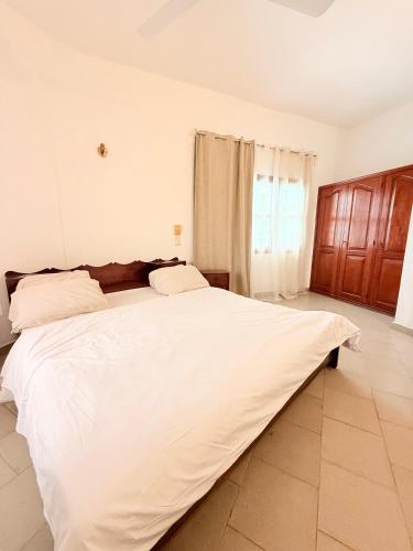 a large white bed in a white bedroom at Grand appartement non loin du centre de Cotonou in Godomey