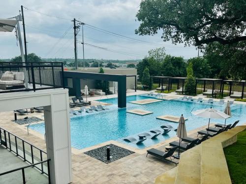 a large swimming pool with lounge chairs and umbrellas at Cozy 1BR Near Domain Pool &Gym in Austin