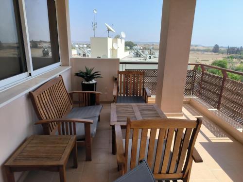 a balcony with wooden tables and chairs and windows at Superior 1 bed apartment in Oroklini with Communal Pool in Voroklini