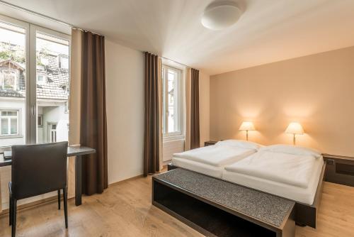 a bedroom with a bed and a desk and a window at Hotel Alpina Luzern in Luzern