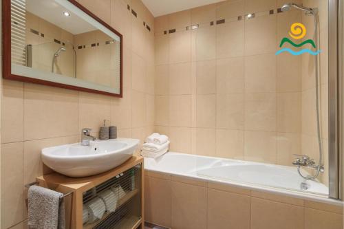 a bathroom with a sink and a tub and a mirror at OurMadeira - Casa da Belita, sea-view in Calheta