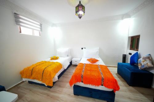 a bedroom with two beds and a blue couch at Dar Al Fanouss in Rabat