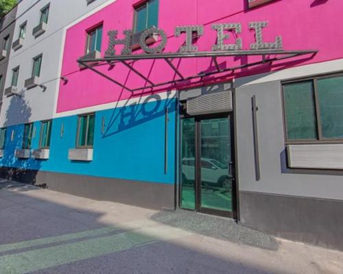 a pink and blue building with a sign on it at Marina Hotel Brooklyn-Broadway in Brooklyn