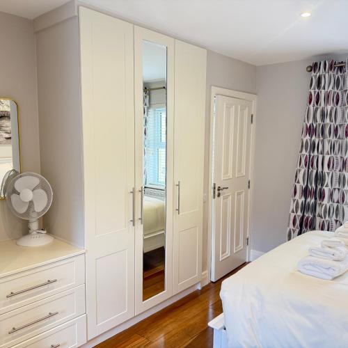 a white bedroom with a closet and a mirror at 3 Fair Hill House centrally located with parking and wifi sleeps 6 in Killarney