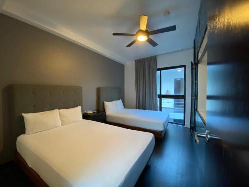 a bedroom with two beds and a ceiling fan at Sole Suites Apartments Playa del Carmen in Playa del Carmen