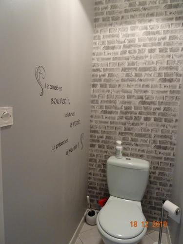 La salle de bains est pourvue de toilettes blanches et d'un mur en briques. dans l'établissement La Petite Pépite, à Saint-Hilaire-de-Riez