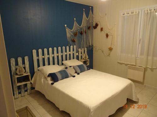- une chambre avec un lit blanc aux murs bleus dans l'établissement La Petite Pépite, à Saint-Hilaire-de-Riez