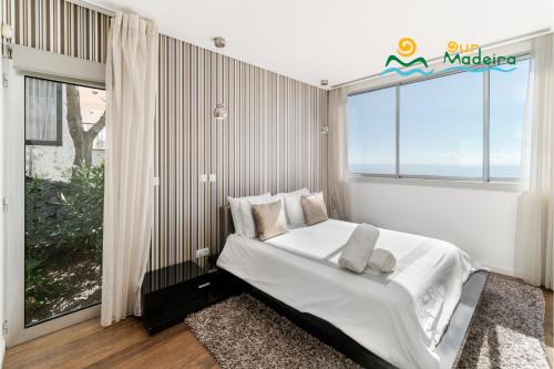 una camera da letto con un letto e una grande finestra di OurMadeira - Fonte do Mar 1, premium a Caniço