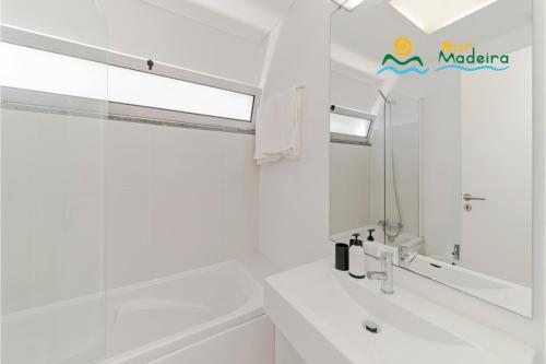 un bagno bianco con lavandino e specchio di OurMadeira - Fonte do Mar 1, premium a Caniço