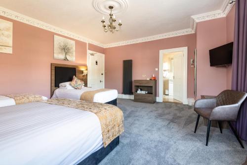 a hotel room with two beds and a chair at Atholl Villa Guest House in Pitlochry
