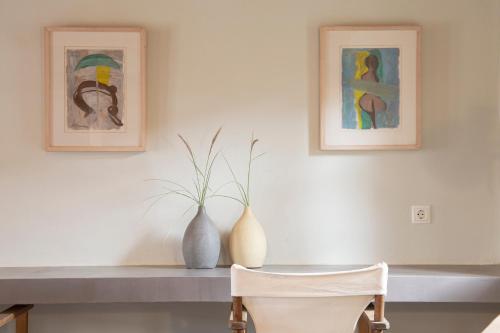 a table with two vases and paintings on the wall at Under The Linden Tree Tinos in Xinára