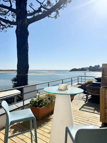 une table et des chaises sur une terrasse avec vue sur l'eau dans l'établissement Luxury ! Villa - Vue mer 180 - Terrasse face océan, à Guidel
