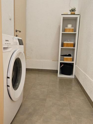 a laundry room with a washing machine and a shelf at Apartmani Mariva in Dicmo