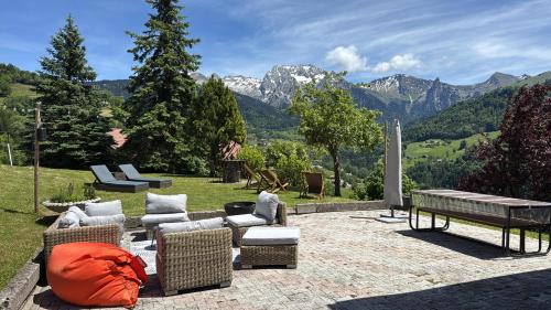 a patio with couches and a bench and mountains at Chalet de Manigod in Manigod
