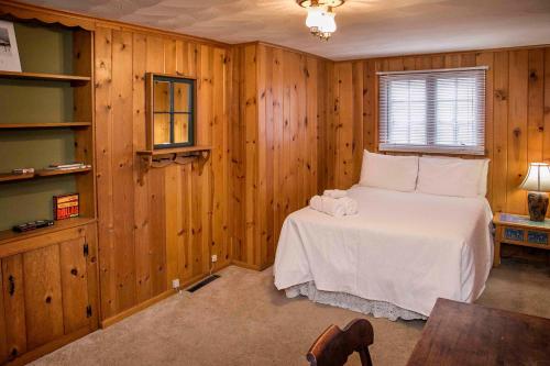 a bedroom with wooden walls and a bed with white sheets at Keuka Sunrise 