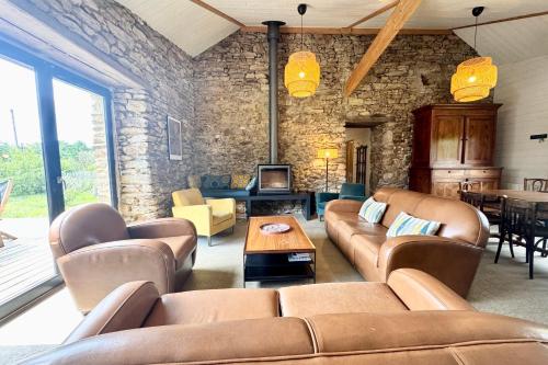Elle comprend un salon doté d'un mobilier en cuir et d'un mur en pierre. dans l'établissement Spacieuse maison bretonne Plage à 3 mi, à Sarzeau